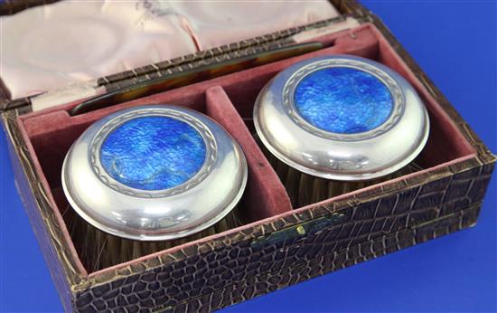 A cased pair of George V Arts & Crafts silver and blue enamel mounted clothes brushes by W.H. Haseler Ltd,, diameter 3in.